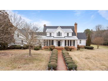 Stately two-story white home featuring a brick walkway, grand front porch, and lush, landscaped grounds at 1200 Spring Valley Lake Rd, Henderson, NC 27536