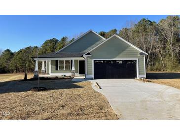 Newly constructed home with green vinyl siding and a black garage door at 125 Hydrangea Ln, Benson, NC 27504
