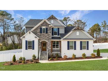 Charming two-story home featuring a stone facade, manicured lawn, and inviting front porch at 128 S Clearbrook Ct, Angier, NC 27501