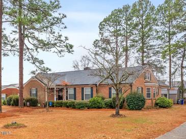 Charming single-story brick home featuring mature trees and lush landscaping, creating a serene and inviting curb appeal at 302 S Pine St, Benson, NC 27504