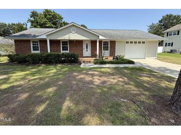 Charming brick home features a well-manicured lawn and an attached two-car garage at 307 Westfield Dr, Dunn, NC 28334