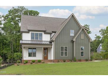 Two-story farmhouse exterior with gray and white siding, a brown door, and a landscaped lawn at 3400 Amelia Grace Dr # 46, Fuquay Varina, NC 27526