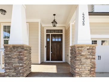 Charming entryway with a dark wood door, stone accents, and craftsman-style columns at 4538 Brighton Ridge Dr, Apex, NC 27539