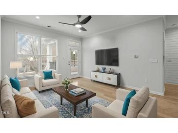 Bright living room with hardwood floors, large windows, and access to a balcony at 105 Fountain Ridge Pl, Holly Springs, NC 27540