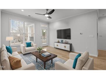 Bright living room featuring light wood floors, a ceiling fan, and ample natural light from large windows at 105 Fountain Ridge Pl, Holly Springs, NC 27540