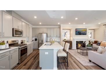 Open concept kitchen features stainless steel appliances and an island at 1878 Sweet Gardenia Way, Apex, NC 27502