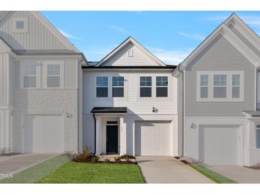 Charming new construction home with attached garage, white siding, and well manicured lawn at 545 Eversden Dr, Zebulon, NC 27597