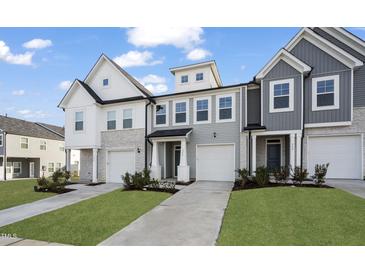 Charming townhome exteriors with a combination of siding, stone accents, and individual garages on a manicured lawn at 556 Eversden Dr, Zebulon, NC 27597