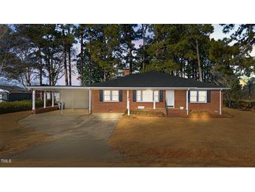 Charming brick home with a covered carport, a well-manicured lawn, and mature trees at 205 N Augusta Ave, Benson, NC 27504