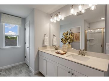 Elegant bathroom with double vanity, large mirror, and a walk-in shower at 119 Siebold St, Garner, NC 27529