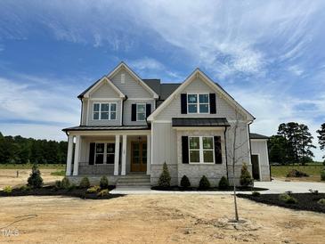 Beautiful two-story home featuring a stone facade, dark shutters, and professionally landscaped front yard at 190 Broadleaf Ln, Louisburg, NC 27549