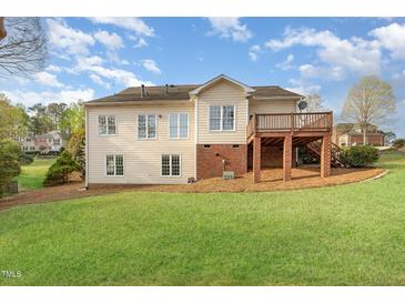 Spacious backyard view featuring a deck, beige siding, and well-manicured lawn perfect for outdoor activities at 306 Neuse Ridge Dr, Clayton, NC 27527