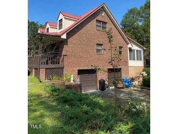 Brick home with attached two-car garage, red roof, and spacious porch at 515 Docs Rd, Lillington, NC 27546