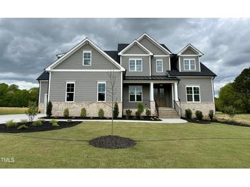 Beautiful two-story home with a manicured lawn and a welcoming brick and gray facade, exuding curb appeal at 90 Firefly Ln, Louisburg, NC 27549