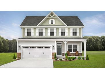 Two-story home with a white garage door, inviting front porch, and manicured lawn at 1024 Country Pasture Cv, Wendell, NC 27591