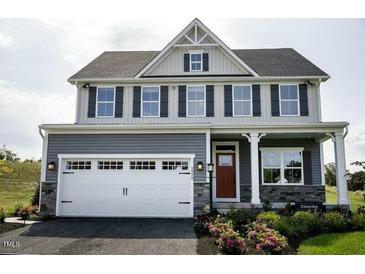 Charming two-story home featuring gray siding, black shutters and a prominent white garage door at 1036 Country Pasture Cv, Wendell, NC 27591