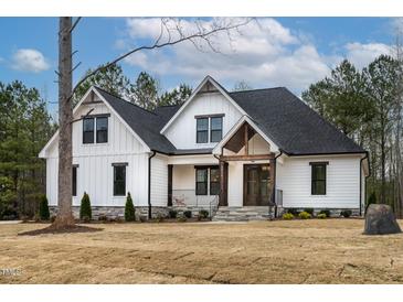 Beautiful two-story modern farmhouse-style home with a manicured lawn and inviting front porch at 3912 Cedar Knolls Dr, Youngsville, NC 27596