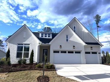 Charming one-story white brick home with a two-car garage, a landscaped front yard and a blue sky at 200 Regency Ridge Dr, Holly Springs, NC 27540