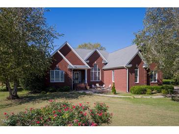Brick home with landscaping, large yard, and a spacious front porch at 555 House Rd, Kenly, NC 27542