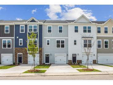 Charming new townhomes feature varied siding and attached garages with a sidewalk and small trees lining the street at 865 Parc Townes Dr # 4, Wendell, NC 27591