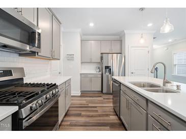 Bright kitchen with gray cabinets, stainless steel appliances, and light countertops at 1008 Ashton Oak Ct, Durham, NC 27703