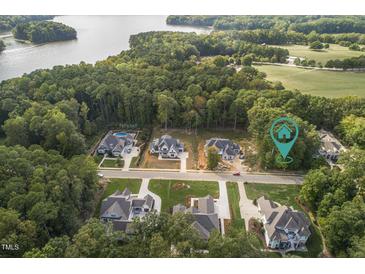 Stunning aerial view of luxurious homes surrounded by lush trees and serene lake at 172 Bonica Creek Dr, Garner, NC 27529