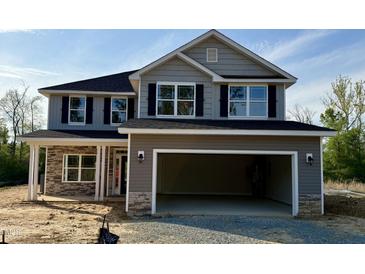 Two-story home featuring stone accents, an attached two-car garage, black shutters and a covered porch at 217 Lake Edge Dr, Lillington, NC 27546