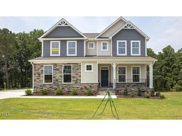Two-story home with stone and siding accents, featuring a welcoming front porch at 72 Demascus Way, Four Oaks, NC 27524