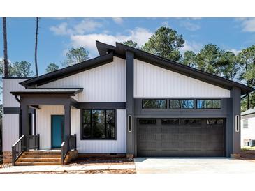 Contemporary home with modern architecture, dark window frames, and gray garage door at 2662 Sledge Rd, Louisburg, NC 27549