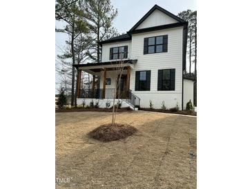 Beautiful two-story home boasting white siding, black accents, a welcoming porch, and a well-manicured front yard at 318 Hinton St, Apex, NC 27502