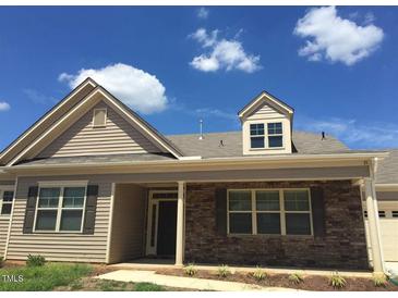 Tan two-story house with brown brick accents and a covered porch at 13 E Milan Ct, Clayton, NC 27527