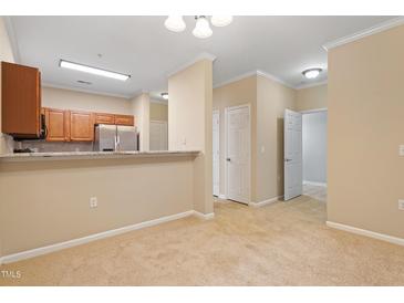 Bright living room showcasing neutral carpet, white trim, and an open floorplan flowing into the kitchen at 2621 Oldgate Dr # 105, Raleigh, NC 27604