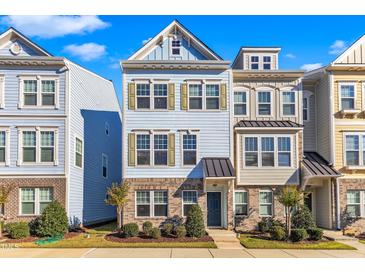 Three-story townhome with light blue and brick exterior, landscaped front yard at 323 Great Northern Sta, Apex, NC 27502