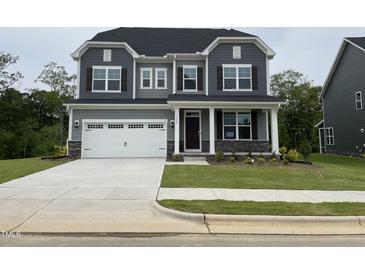 Charming two-story home with gray siding, stone accents, manicured lawn, and a two car garage at 1528 Goldfinch Perch Ln, Knightdale, NC 27545