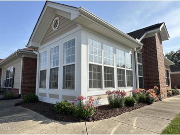 Bright sunroom addition with large windows and brick exterior and colorful landscaping at 4712 Fox Fern Ln, Raleigh, NC 27604