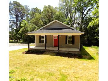 Charming single-story home featuring a covered porch and a striking red front door at 104 Halifax Rd, Louisburg, NC 27549