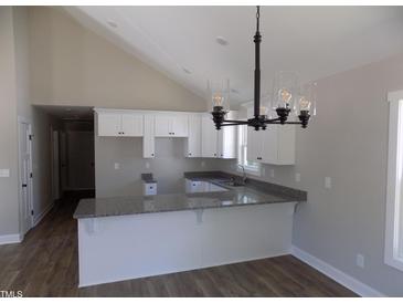 Bright kitchen features granite countertops, white cabinetry, and modern pendant lighting at 104 Halifax Rd, Louisburg, NC 27549