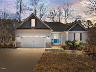 Charming single-story home with a two-car garage, blue door, and manicured landscaping at 1119 Sagamore Dr, Louisburg, NC 27549