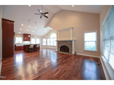 Bright living room featuring hardwood floors, stone fireplace, and views into the spacious open kitchen at 1508 Woods Creek Dr, Garner, NC 27529
