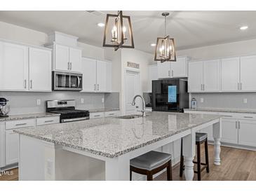 A spacious kitchen features granite counters, stainless appliances, pendant lighting, and stylish white cabinetry at 168 Begonia St, Angier, NC 27501