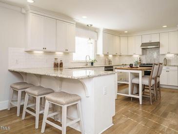 Bright kitchen features white cabinets, granite countertops, a breakfast bar with seating, and stainless steel appliances at 505 Annandale Dr, Cary, NC 27511