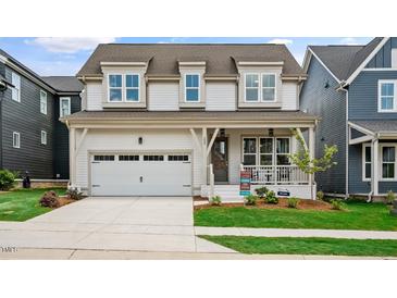 Charming two-story home featuring a covered porch, a two-car garage, and manicured landscaping at 224 Wash Hollow Dr, Wendell, NC 27591