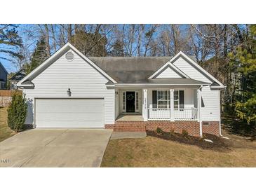 White house with brick accents, a two-car garage, and a covered front porch at 2773 Clifton Avenue, Creedmoor, NC 27522