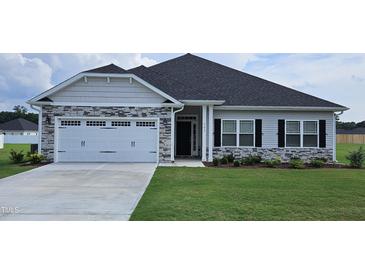 House exterior with stone accents, a two-car garage, and a well-manicured lawn at 40 Northwood Dr, Fuquay Varina, NC 27526