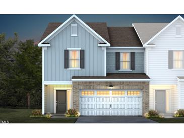 Two-story townhome with light blue and brown siding, white garage door, and landscaping at 291 Broomside Ave, Raleigh, NC 27603