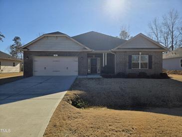 Brick house with 2-car garage, and a well-maintained lawn at 78 Falls Of The Cape Dr, Lillington, NC 27546