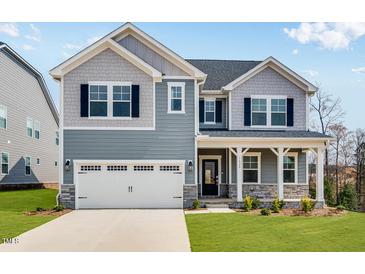Charming two-story home with blue siding, white trim, covered porch, and attached two car garage at 1029 Dillon Lake Dr, Knightdale, NC 27545