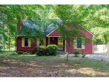 Charming single-story home with red siding, complemented by lush greenery and mature trees at 211 Dwelling Pl, Knightdale, NC 27545