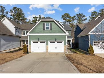 Two-story house with green siding, two-car garage, and a landscaped yard at 104 Spruce Hollow Cir, Spring Lake, NC 28390