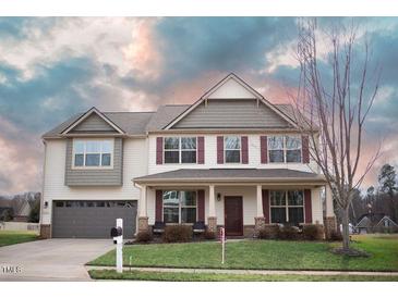 Charming two-story home featuring a well-manicured lawn, attached garage, and inviting front porch area at 241 Fair Oaks Ct, Mebane, NC 27302